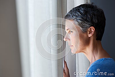 Older woman looking out window Stock Photo