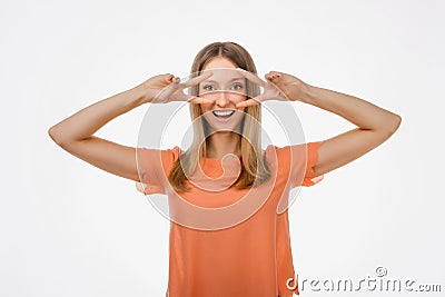 Portrait of optimistic blond girl showing peace sign over eye and smiling white background. Just be cool about it Stock Photo