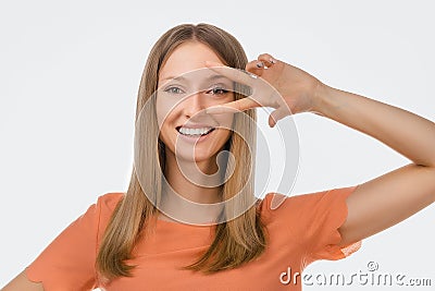 Portrait of optimistic blond girl showing peace sign over eye and smiling, white background. Just be cool about it Stock Photo