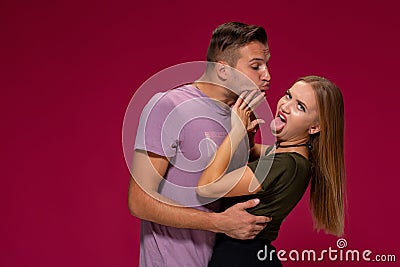 Portrait of outraged displeased woman gesturing to stop with hand while man trying to kiss her on burgundy background Stock Photo