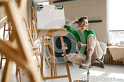 Portrait of overjoyed smiling woman artist holding paintbrush on nose Stock Photo