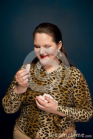 Portrait of a overweight girl with sweets in her hands. Leopard blouse. Stock Photo