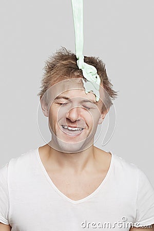 Paint falling on young Caucasian man`s head against gray background Stock Photo