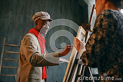 Portrait painter at the easel draws female model Stock Photo