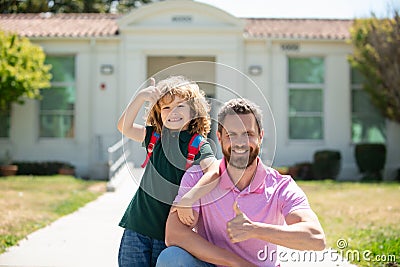 Portrait of parent and pupil with thumbs up of primary school go hand in hand. Teacher in t-shirt and cute schoolboy Stock Photo