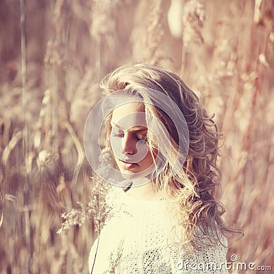 Portrait of pensive beautiful blonde girl in a field in white pullover, the concept of health and beauty Stock Photo