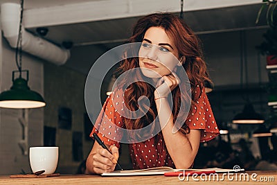 portrait of pensive blogger sitting at table with notebook Stock Photo