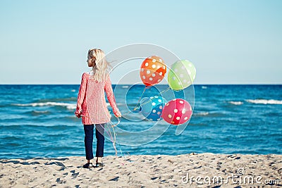 Portrait of pensive teenager white Caucasian child kid with colorful bunch of balloons, standing on beach on sunset Stock Photo