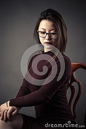 Portrait pensive young girl sitting on chair Stock Photo