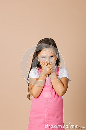 Portrait photo of female kid closing mouth with hands not talk with others with shining eyes and sullen look looking at Stock Photo