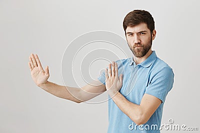 Portrait of playful charming european man who acts like ninja or karate fighter, standing half-turned in defence pose Stock Photo