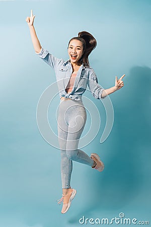 Portrait of playful crazy girl jumping in the air looking at camera enjoying weekend having perfect mood on light blue background Stock Photo