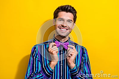Portrait of pleasant cheerful gentleman dressed stylish shirt touching bow tie smiling isolated on vibrant yellow color Stock Photo