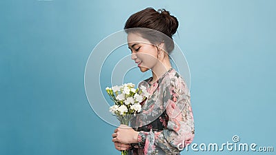 Portrait of pleasant looking woman has minimal make up broad smile receives flowers on special occasion isolated over light Stock Photo