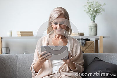 Portrait of pleasant middle aged woman using tablet. Stock Photo