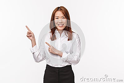 Portrait of polite nice asian lady in formal clothes, ointing fingers upper left corner and smiling camera, click here Stock Photo