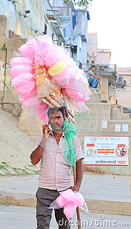 A portrait of a poor young Hard working man selling cotton candy taffy to tourists. Editorial Stock Photo