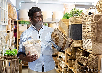 Positive african american man choosing storage wicker basket at store Stock Photo