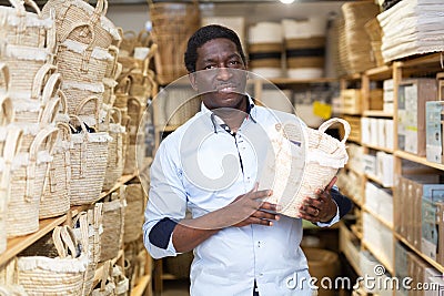 Positive african american man choosing storage wicker basket at store Stock Photo