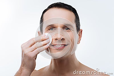 Portrait of a positive delighted man holding a cotton pad Stock Photo