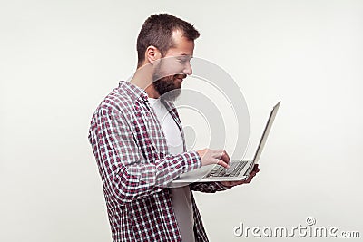 Portrait of positive freelancer, happy bearded man standing with laptop and typing on keyboard. white background Stock Photo