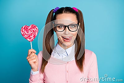 Portrait of positive funny funky girl high school student hold heart shape lollipop want eat lick lips tongue wear good Stock Photo