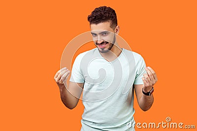 Portrait of positive handsome brunette man showing italian gesture or money sign with hands. indoor studio shot isolated on orange Stock Photo