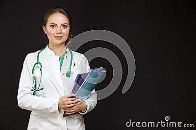 Portrait of Positive Professional Female GP Doctor Posing in Doctor`s Smock and Endoscope Against Black Stock Photo