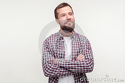 Portrait of positive thoughtful bearded man standing with crossed hands, looking aside with dreamy happy face. white background Stock Photo