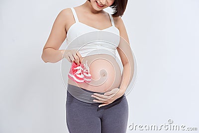 A portrait of a Pregnant woman with a pair of pink knit baby shoes Stock Photo