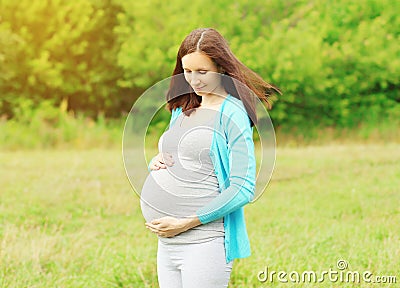 Portrait of pregnant young woman outdoors in warm summer Stock Photo