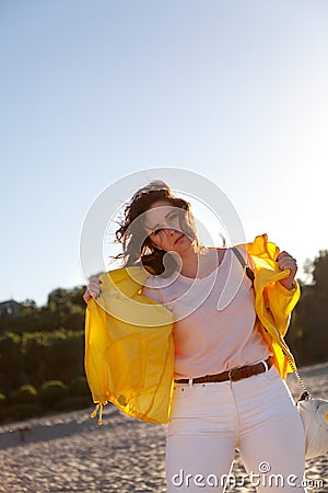 Beautiful plus size woman in yellow jacket on sandy beach Stock Photo