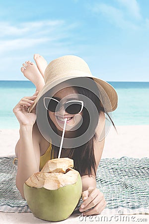 Female drinking coconut water on the beach Stock Photo