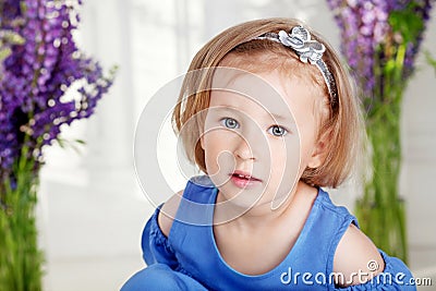 Portrait of pretty little emotion girl among violet flowers.Clouse up picture of beautiful girl Stock Photo