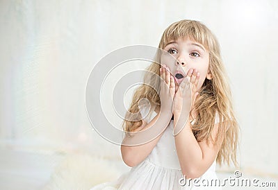 Portrait of pretty little girl in white dress , she is surprised and put her hands on cheeks. Stock Photo