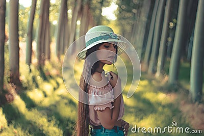Portrait of a pretty long haired brunette hispanic girl wearing white sun hat pink blouse and short blue jeans Stock Photo