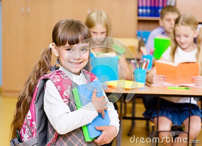 Portrait of pretty preschool girl with books in classroom Stock Photo
