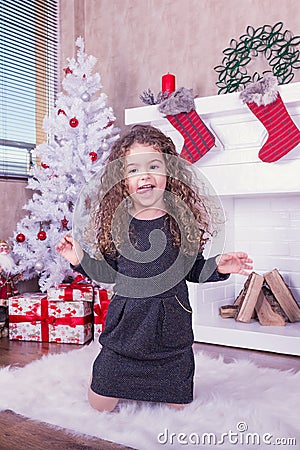 Portrait of pretty sweet little girl near a fireplace in Christmas Stock Photo