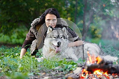 Portrait of a pretty white woman with an Alaskan Malamute dog by the fire Stock Photo