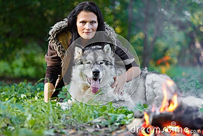 Portrait of a pretty woman with an Alaskan Malamute dog by the fire Stock Photo