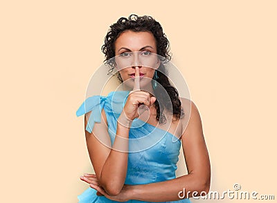 Portrait of a pretty young brunet woman showing silence gesture in blue puffy dress with bow push isolated Stock Photo