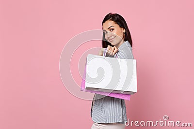 Portrait of pretty young woman in striped jacket holding package bag with purchases after shopping isolated on pink Stock Photo