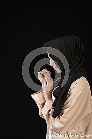 portrait in profile Beautiful Muslim girl in a black scarf on her head on a black background Stock Photo