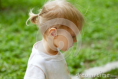 Portrait in profile of cute blond toddler girl in a windy summer day wearing ponytail Stock Photo