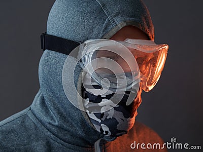 Portrait of protesting male hiding his face behind scarf and protective goggles looking away. Stock Photo