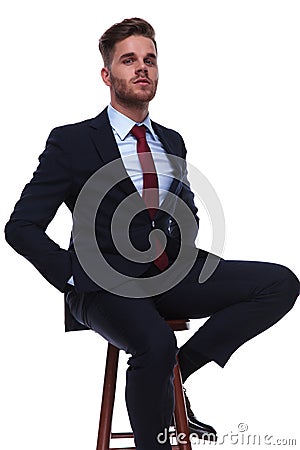Portrait of proud businessman sitting on wooden stool Stock Photo