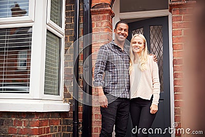 Portrait Of Proud Young Couple Standing Outside First Home Together Stock Photo