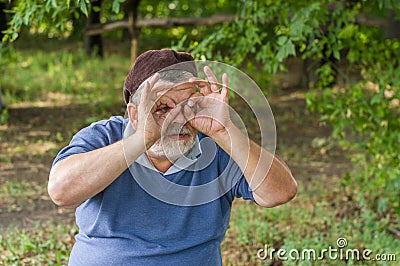 Portrait of senior making gesture like looking through binocular Stock Photo