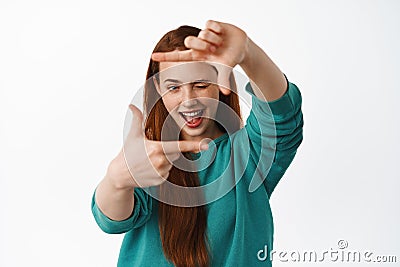 Portrait of redhead woman look through hands frames with creative eye, measure something, searching for perfect spot for Stock Photo