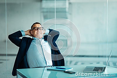 Portrait of relaxed senior manager sitting at office and leaning back. Stock Photo
